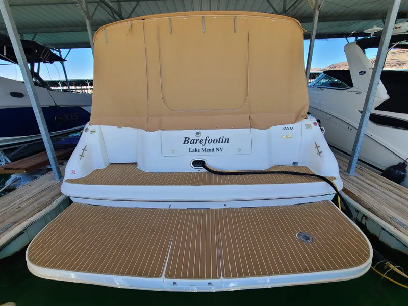 Slide: The Image of 1998 Sea Ray 400 Sundancer docked, rear view with tan cover, named "Barefootin". - 3