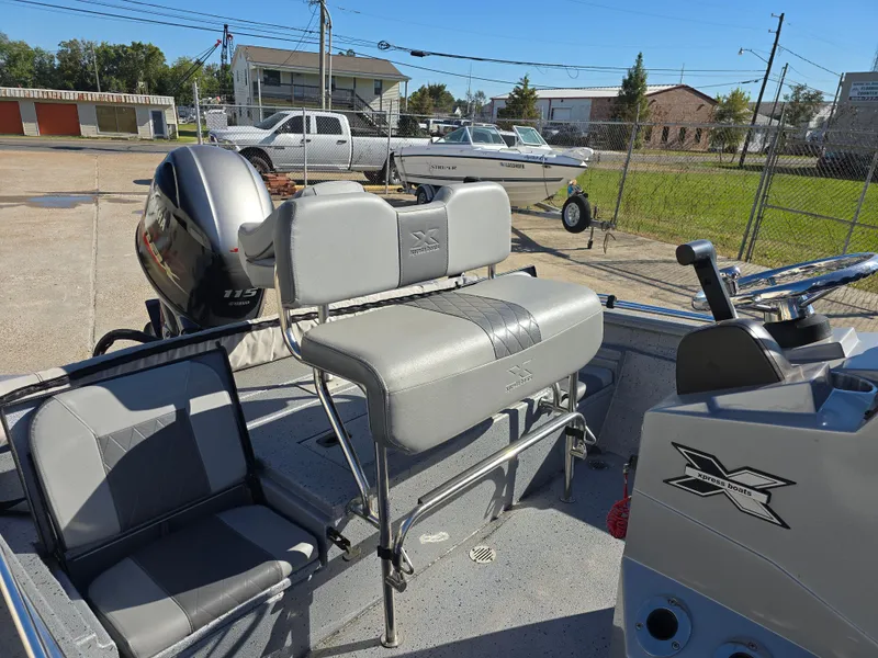 Slide: The Image of 2022 Xpress H20B boat interior with seating and motor, parked outdoors. - 10