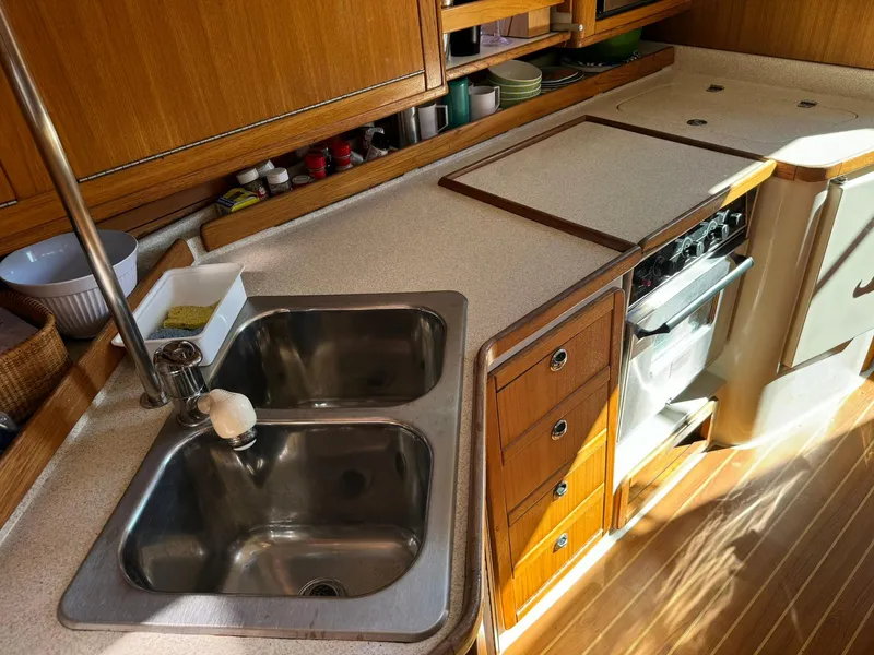 Slide: The Image of 2004 Catalina 42 MkII yacht kitchen with dual sinks, stove, and wooden cabinetry. - 47