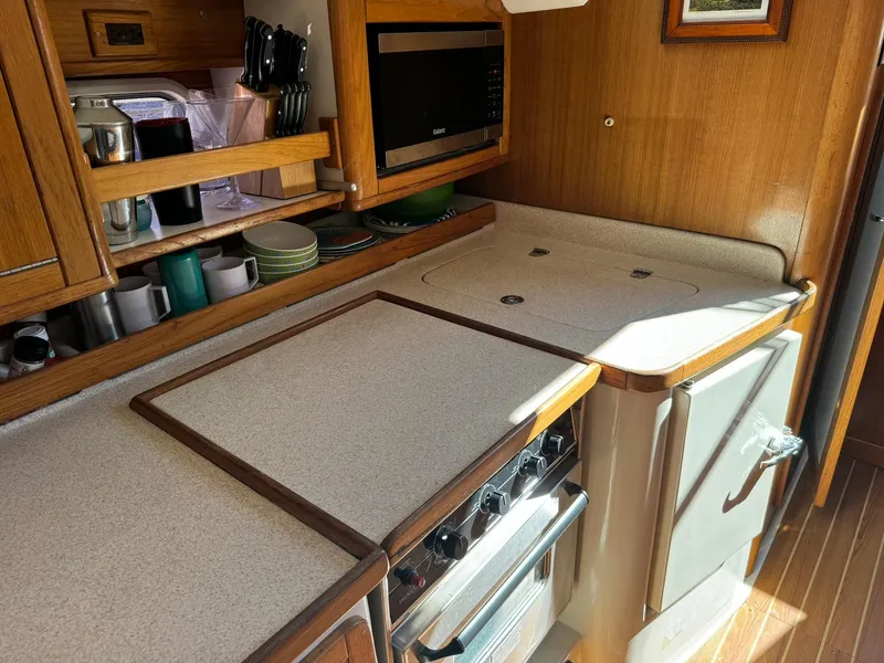 Slide: The Image of 2004 Catalina 42 MkII yacht kitchen with stove, microwave, and wooden cabinetry. - 48