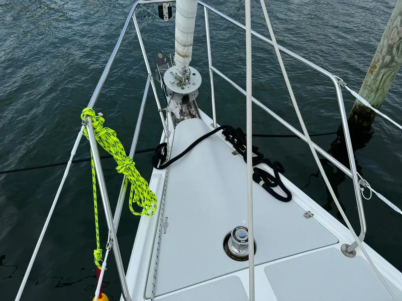 Slide: The Image of Bow of 2004 Catalina 42 MkII sailboat with ropes and railing, docked on calm water. - 7