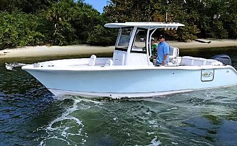 Slide: The Image of 2018 Sea Hunt Ultra 255 SE boat cruising near a lush shoreline. - 48