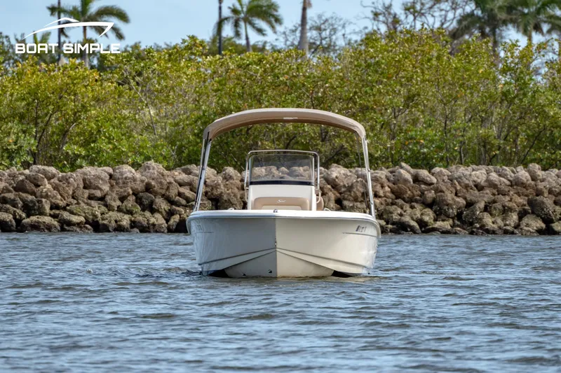 Slide: The Image of 2021 Scout 195 Sportfish boat on water, surrounded by rocks and greenery. - 2