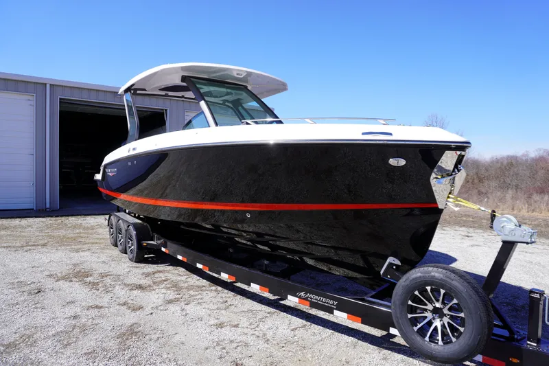 Slide: The Image of 2025 Monterey Elite 30 OB boat on trailer, black with red stripe, parked outdoors. - 5