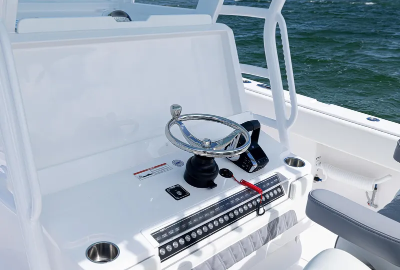 Slide: The Image of 2025 Invincible 35 Catamaran helm with steering wheel and controls, ocean backdrop. - 20
