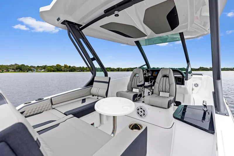 Slide: The Image of 2025 Monterey Elite 27 OB boat interior with seating and table on a calm lake. - 4