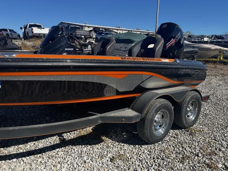 Slide: The Image of 2019 Nitro Z18 boat with orange and black design on gravel. - 2