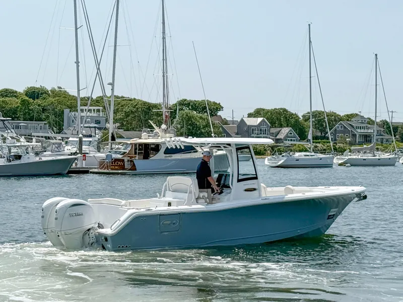 Slide: The Image of 2025 Sea Hunt Ultra 275 SE boat cruising in a marina with sailboats in the background. - 2