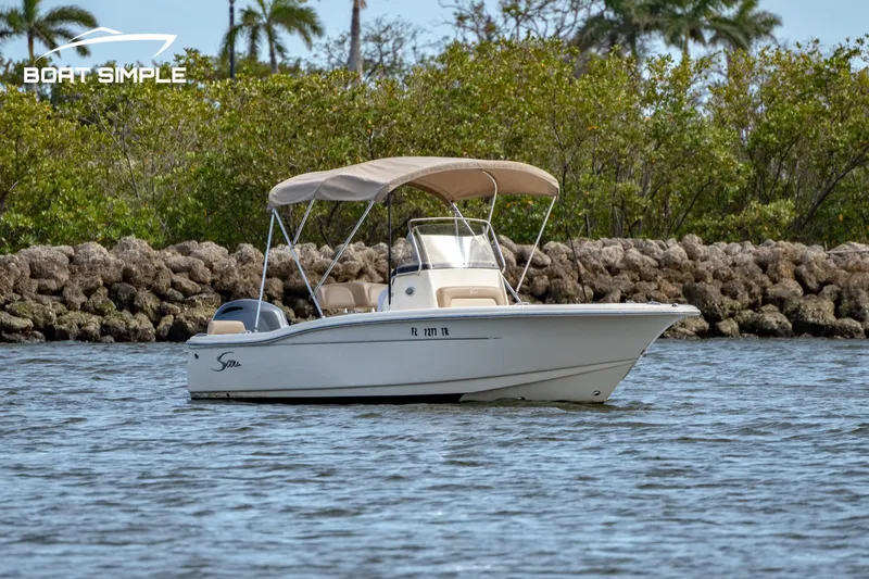 Slide: The Image of 2021 Scout 195 Sportfish boat on calm water with lush greenery background. - 4