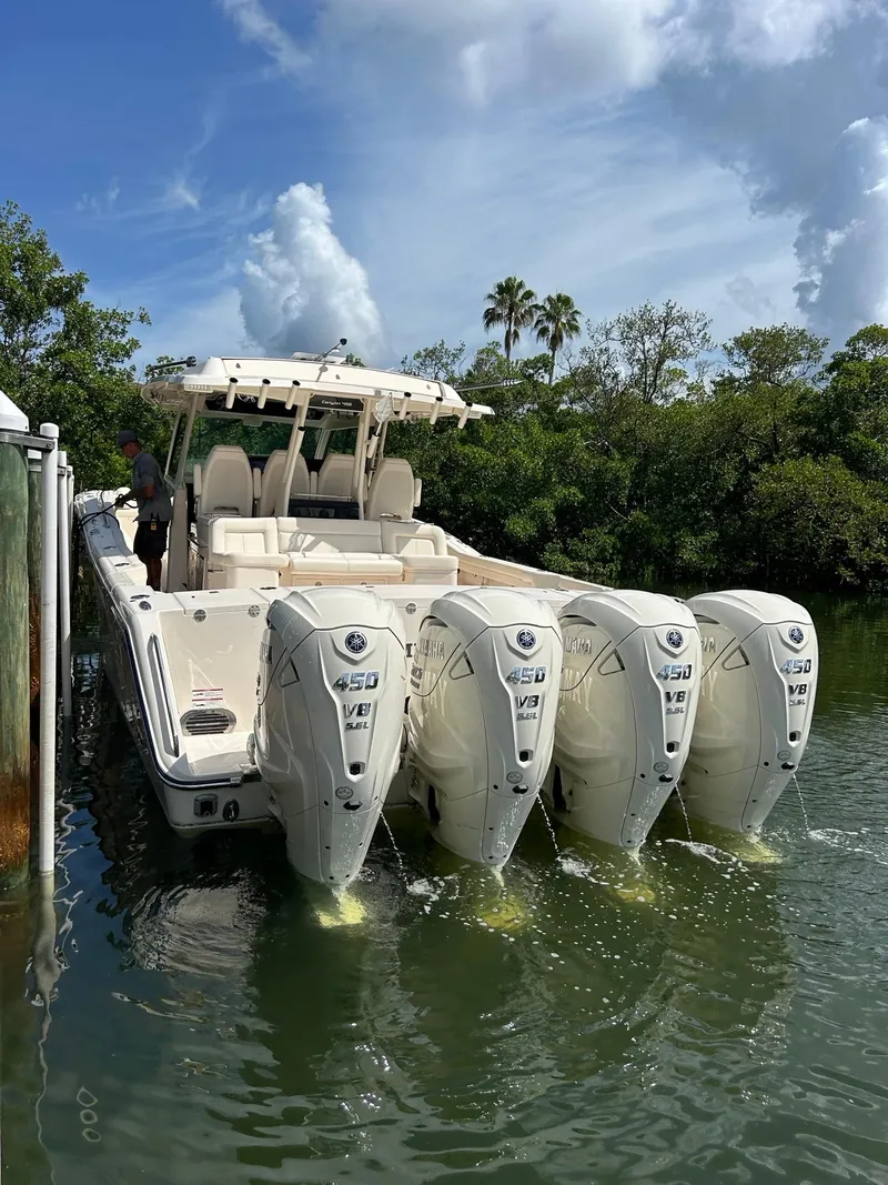 Slide: The Image of 2024 Grady-White Canyon 456 boat with four powerful outboard engines docked in scenic waters. - 21