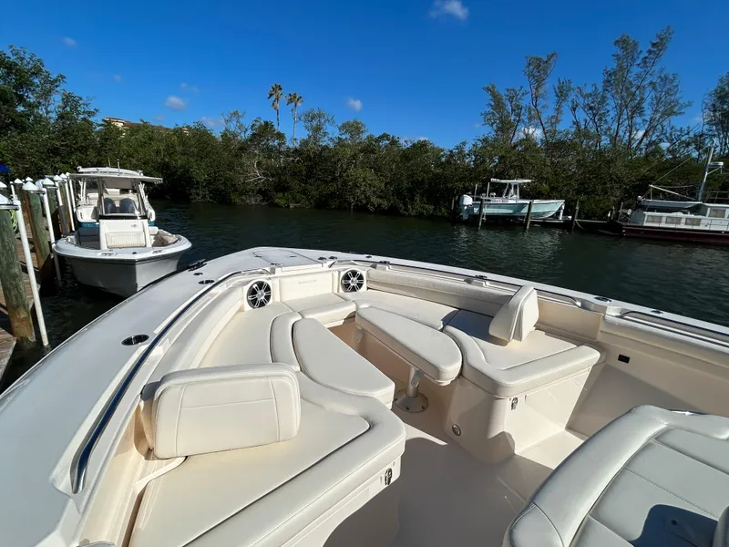 Slide: The Image of 2024 Grady-White Canyon 456 boat with luxurious seating, docked by lush greenery. - 7