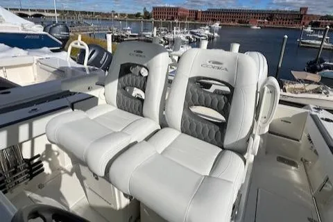 Slide: The Image of 2025 Cobia 265 Center Console Open with plush seating at a marina. - 40