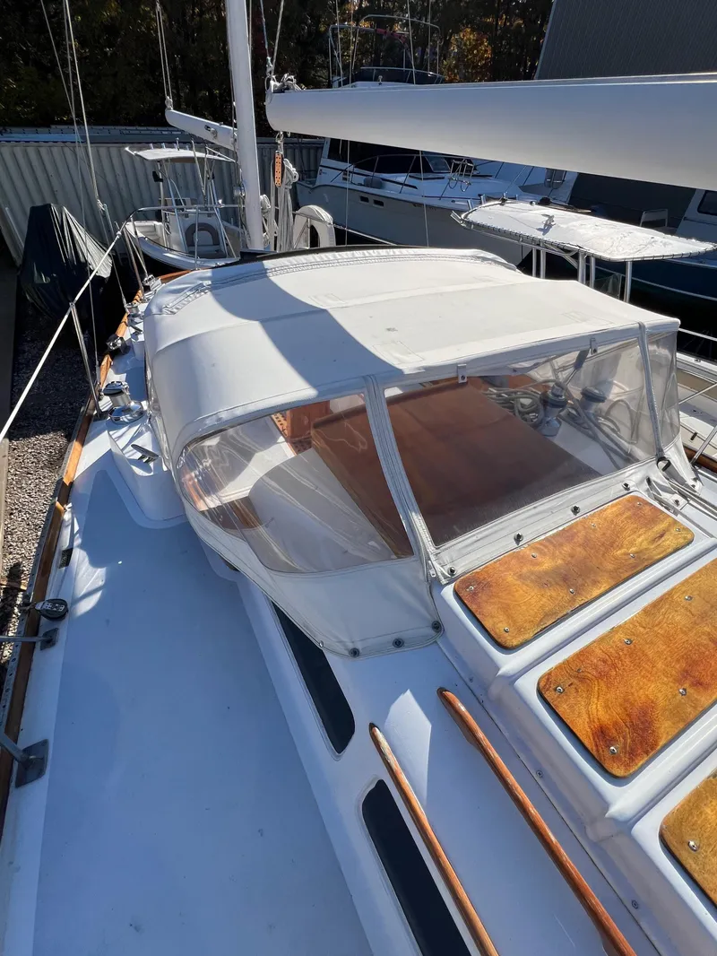 Slide: The Image of 1967 Hinckley Bermuda sailboat with white deck and wooden accents, docked in a marina. - 19