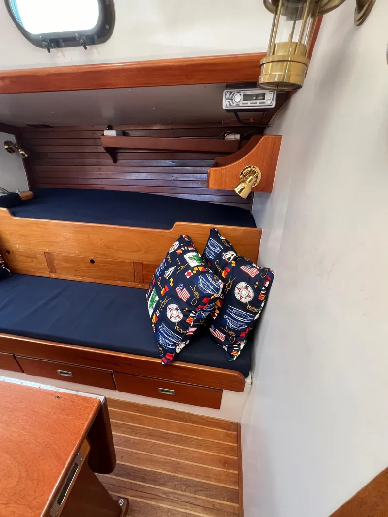 Slide: The Image of 1967 Hinckley Bermuda interior with wooden finish, blue cushions, and nautical-themed pillows. - 42