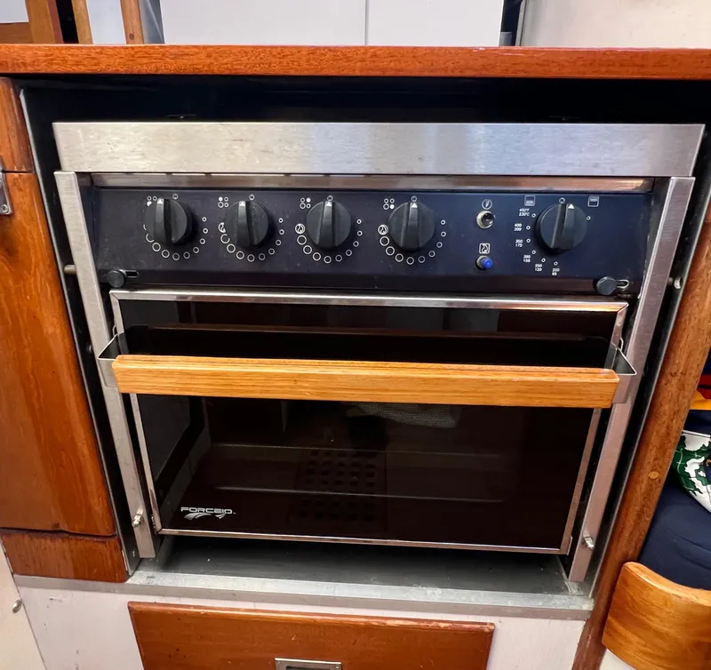Slide: The Image of Vintage 1967 Hinckley Bermuda yacht kitchen oven with wooden accents and control knobs. - 46