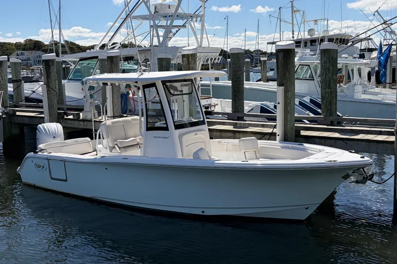 Slide: The Image of 2025 Sea Hunt Ultra 245 SE boat docked in a marina under a clear sky. - 8