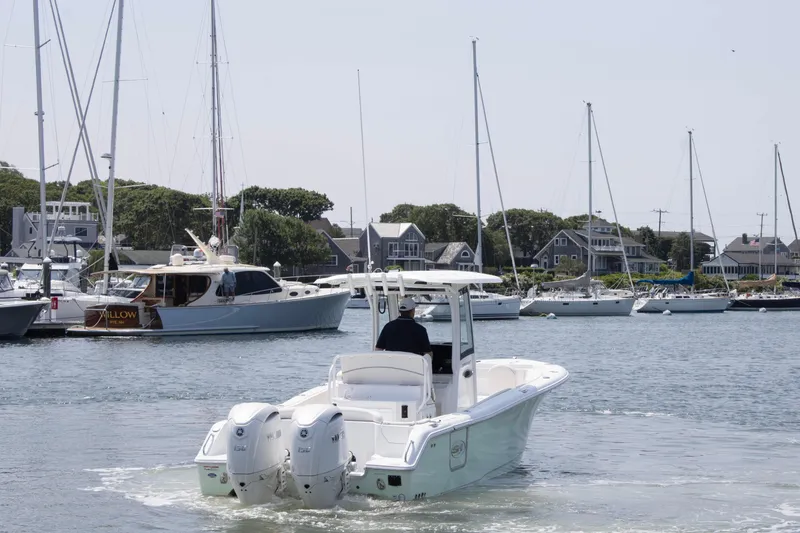 Slide: The Image of 2025 Sea Hunt Ultra 265 SE boat navigating a marina with sailboats in the background. - 2