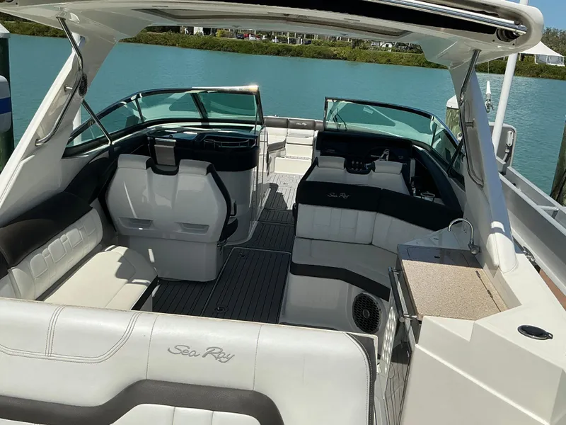 Slide: The Image of 2016 Sea Ray 350 SLX boat interior with white seating and open deck, docked by blue water. - 27