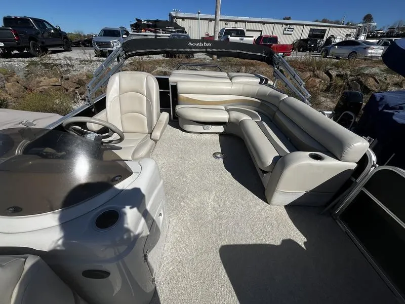 Slide: The Image of 2011 South Bay 522CR pontoon boat interior with beige seating and steering console. - 4