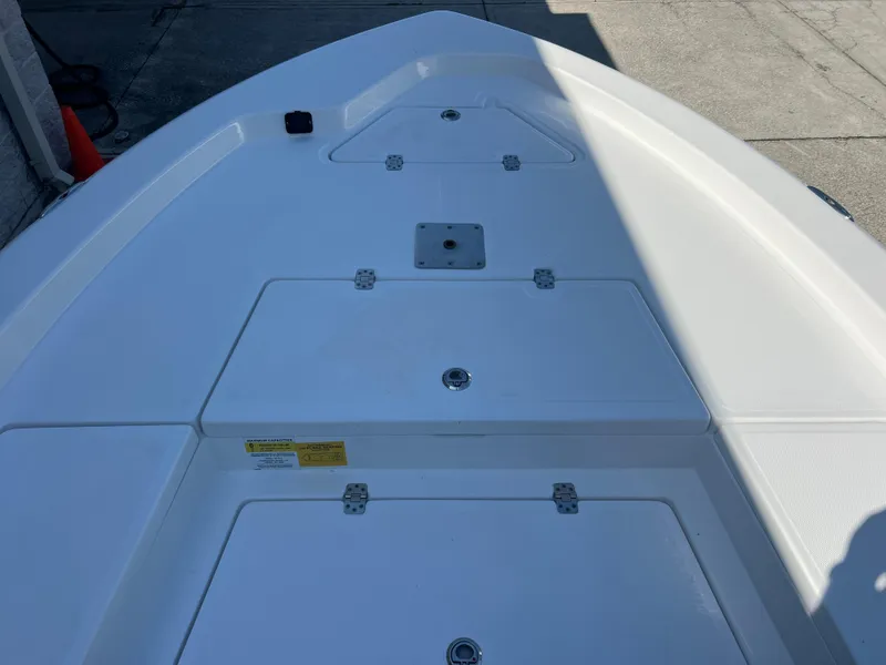 Slide: The Image of 2025 NauticStar 224 Bay boat deck with storage compartments in sunlight. - 10
