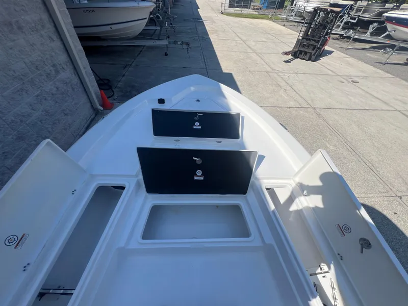 Slide: The Image of 2025 NauticStar 224 Bay boat with open storage compartments, docked outdoors. - 11