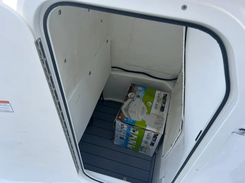 Slide: The Image of Storage compartment in 2025 NauticStar 224 Bay boat with portable toilet box. - 16