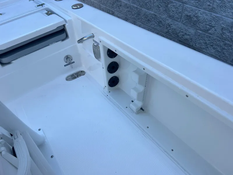 Slide: The Image of 2025 NauticStar 224 Bay boat interior, featuring storage compartments and rod holders. - 18