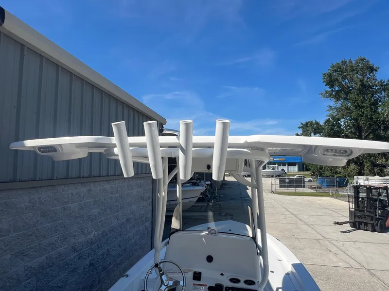 Slide: The Image of 2025 NauticStar 224 Bay boat with T-top and rod holders, docked outdoors. - 19