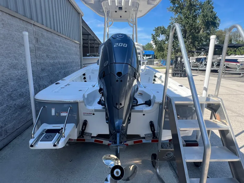 Slide: The Image of 2025 NauticStar 224 Bay boat with powerful outboard motor, docked near a metal staircase. - 21