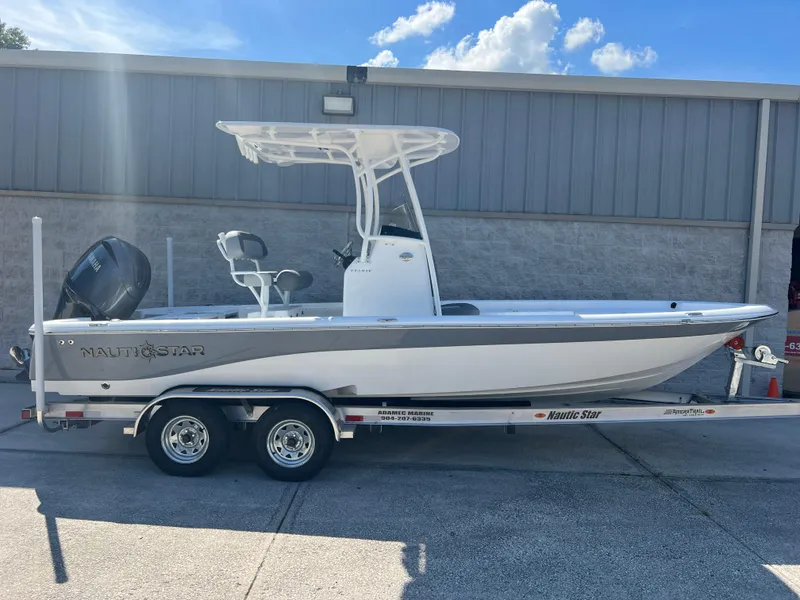 Slide: The Image of 2025 NauticStar 224 Bay boat on trailer, parked outdoors under a clear sky. - 22