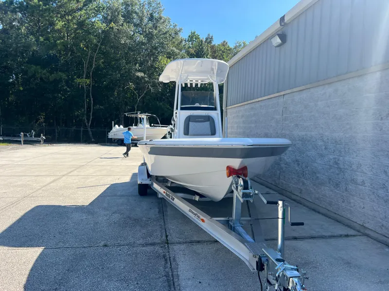 Slide: The Image of 2025 NauticStar 224 Bay boat on trailer, parked outdoors near a building. - 24