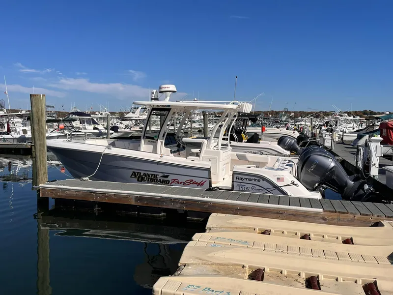 Slide: The Image of 2023 Robalo R302 Center Console boat docked at a marina under clear blue skies. - 7