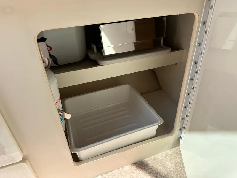 Slide: The Image of Storage compartment in a 2000 Formula 330 SS boat, featuring a fire extinguisher and plastic container. - 30