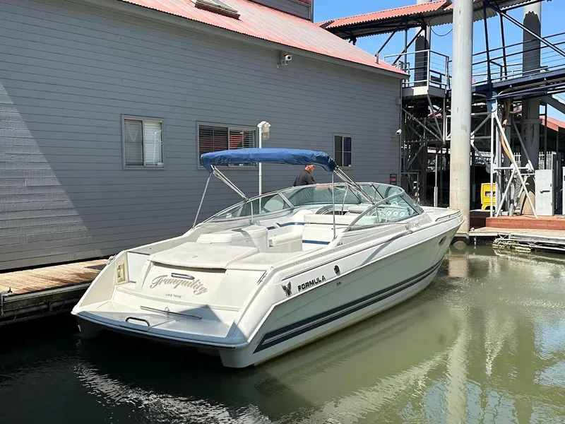 Slide: The Image of 2000 Formula 330 SS boat docked near a building, featuring a blue canopy. - 34