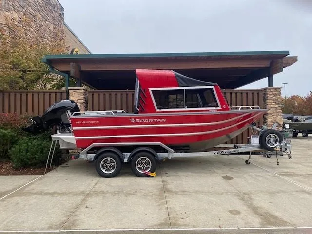The Image of Red 2025 Spartan 185 Astoria boat on trailer, parked outdoors. - 1