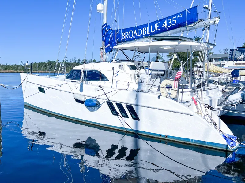 Slide: The Image of 2010 Broadblue 435 catamaran docked in a marina, reflecting on calm water. - 2