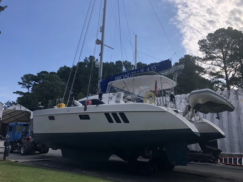 Slide: The Image of Broadblue 435 catamaran from 2010 on land, surrounded by trees and clear sky. - 8