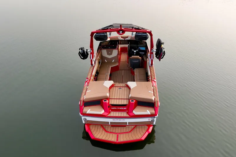 Slide: The Image of 2024 Nautique GS22 boat on calm water, featuring red and beige interior design. - 3