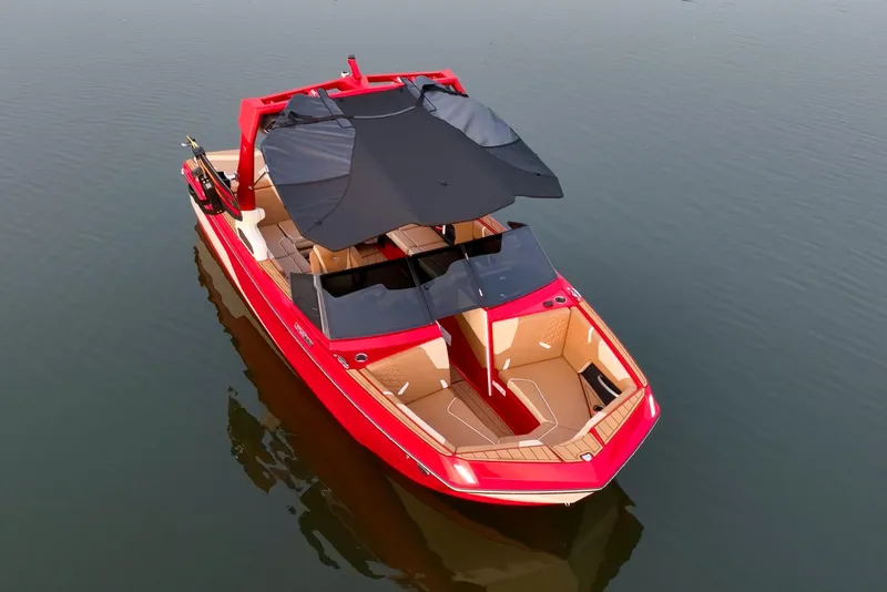 Slide: The Image of 2024 Nautique GS22 boat, red exterior, black canopy, on calm water. - 4
