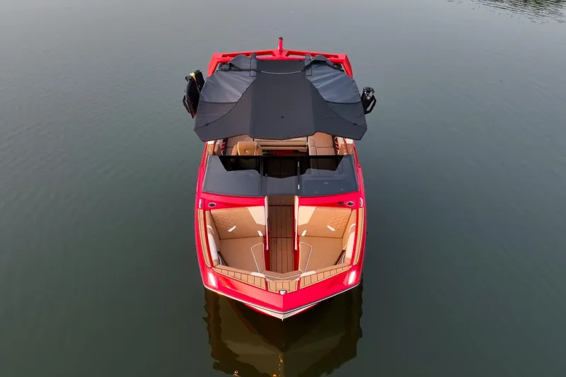Slide: The Image of 2024 Nautique GS22 boat on calm water, top view, red exterior, black canopy. - 6