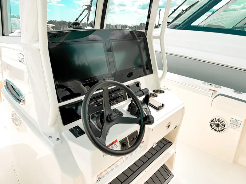 Slide: The Image of 2025 Cobia 285 Center Console boat dashboard with steering wheel and electronic displays. - 13