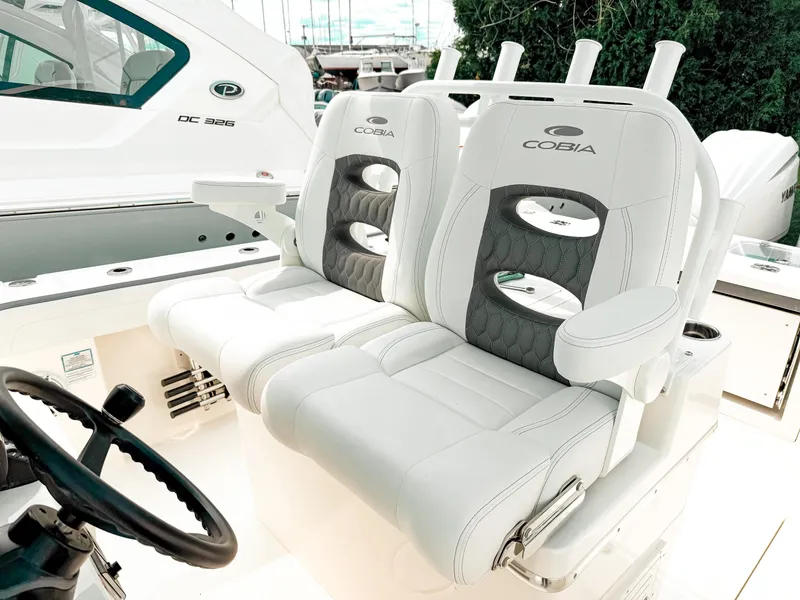 Slide: The Image of 2025 Cobia 285 Center Console boat with luxurious white seating and steering wheel. - 14