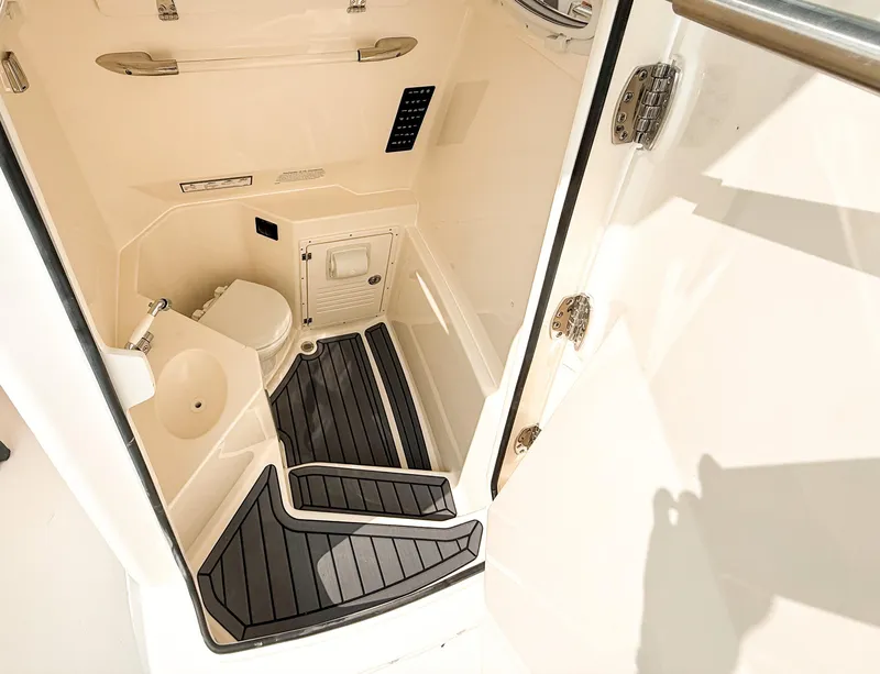 Slide: The Image of 2025 Cobia 285 Center Console boat interior with toilet and sleek flooring. - 15