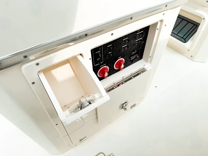 Slide: The Image of 2025 Cobia 285 Center Console control panel with storage compartment and switches. - 25