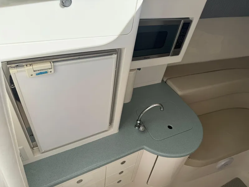 Slide: The Image of 2011 Intrepid 370 Cuddy interior with kitchenette, featuring fridge, sink, and microwave. - 14