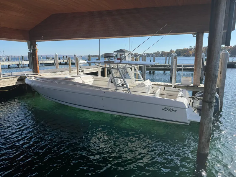 Slide: The Image of 2011 Intrepid 370 Cuddy boat docked under a wooden canopy. - 2