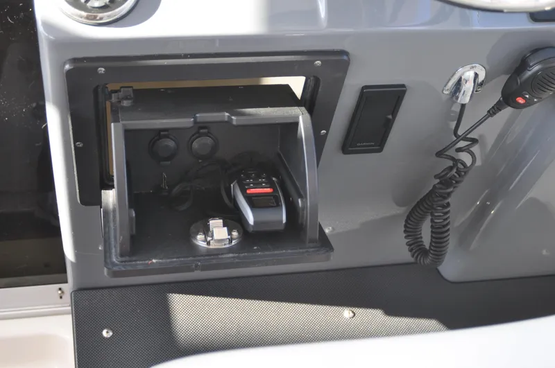 Slide: The Image of 2014 Pursuit OS 315 Offshore boat dashboard with storage compartment and radio equipment. - 12