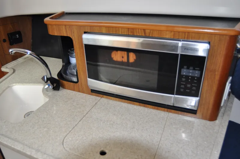 Slide: The Image of 2014 Pursuit OS 315 Offshore boat kitchen with sink and microwave. - 16