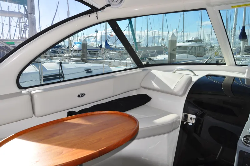 Slide: The Image of Interior of 2014 Pursuit OS 315 Offshore boat with wooden table and marina view. - 6