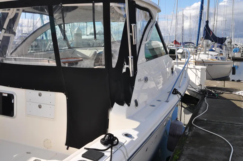 Slide: The Image of 2014 Pursuit OS 315 Offshore boat docked at marina, featuring sleek design and black canopy. - 9